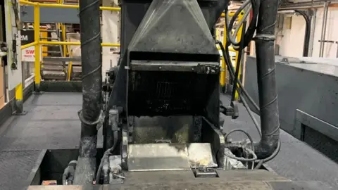 A large metal machine with a wide opening and large tubes on either side.