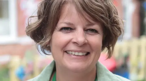 Caroline Gratrix A headshot of Ruth Perry, head teacher of Caversham Primary School. She is smiling at the camera and wearing a green jacket. Her hair is brown, cropped and worn in curls