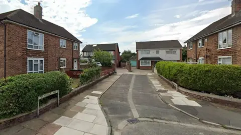 A small no-through street with brick houses on either side of it. 