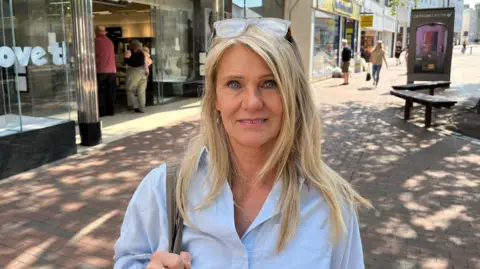 Shopper, Jackie Lamb, stands in front of Marks & Spencer in the pedestrianised area of Tunbridge Wells town centre.