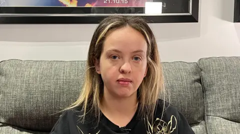 BBC Danielle Alexander. She has blonde and brown hair and is wearing a T-shirt decorated with Disney characters.