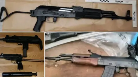 National Crime Agency Firearms including an AK47 assault rifle and Skorpion and Uzi sub-machine guns are displayed on wooden tables next to police evidence bags
