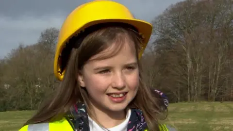 Scarlett seen smiling while wearing a hard hat and high-vis jacket