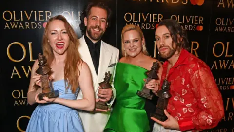 Getty Images Natasha Hodgson, Felix Hagan, Zoe Roberts and David Cumming, winners of the Best New Musical award for "Operation Mincemeat", pose backstage during The Olivier Awards 2024 at the Royal Albert Hall on April 14, 2024 in London, England