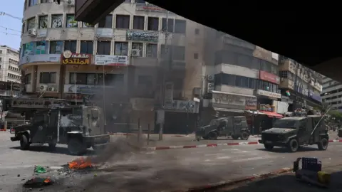 EPA Military vehicles move in the street during an Israeli army operation in the West Bank city of Nablus