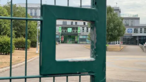BBC/Sarah-May Buccieri A school building in the background, looking through a green gate in the foreground.