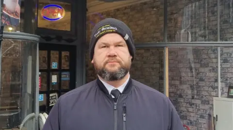 Martin Griffiths Martin Griffiths, wearing a wool hat and a jacket, standing with his hands in his pockets in front of the High Street Feeder cafe, near where the incident took place.