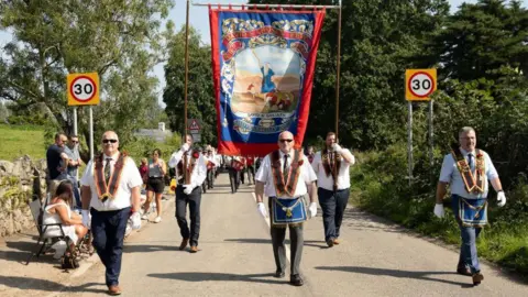 Pacemaker Members of the Royal Black Institution carrying a banner and marching down a street in Killyleagh
