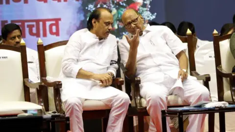 Getty Images Ajit Pawar (left) with his uncle Sharad Pawar. Both lean towards each other as they sit on white cushioned chairs wearing white kurtas