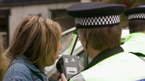 Policeman giving breathalyser test a driver in a drink driving awareness program.