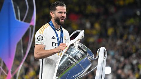 Nacho celebrates with the Champions League trophy smiling with an open mouth and squinted eyes