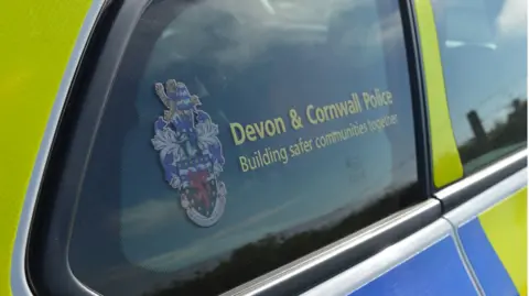 A picture of the side window of a police car. It has the Devon and Cornwall police logo on it.