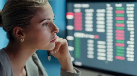 Close up of a blonde woman looking at Bloomberg terminal while holding a pen