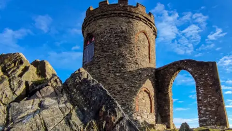 Bradgate Park Trust Old John, a tower dating back to 1784, pictured in the bright sunshine. There are blue skies and a few scattered clouds.