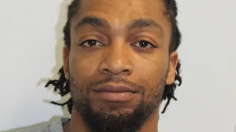 Metropolitan Police A Met Police custody image of Omar Wilson, a man with braided dark hair wearing grey t-shirt