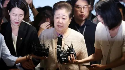 Reuters Han Hak-ja, the leader of the Unification Church, walks through a media scrum as she arrives at the special prosecutors' office for questioning over bribery allegations