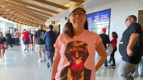 Trump supporter Maureen Liantonio wears a shirt featuring Trump wearing pink sunglasses and blowing bubble gum.