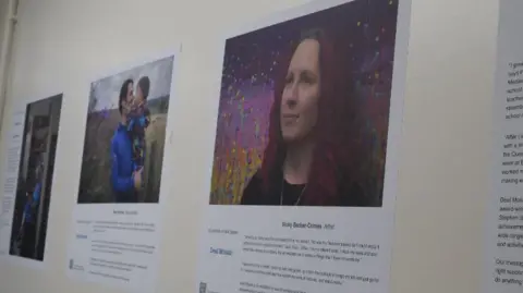 Nottingham University Hospitals Different people in the exhibition with a different story on a wall of a hospital corridor