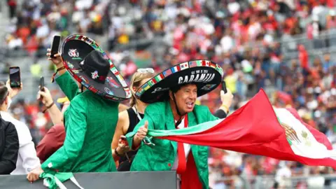 A fan waves the Mexico flag during the drivers' parade before last year's Mexico City Grand Prix 