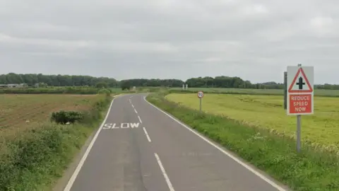 A street view of the A618 - it is a single carriageway with farmer's fields at either side