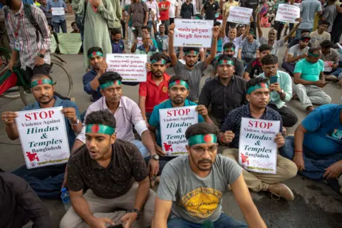 Getty Images People protesting in Bangladesh after the resignation of Sheikh Hasina. They hold up signs saying stop violence against Hindus and Temples Bangladesh on 8th August 2024. 