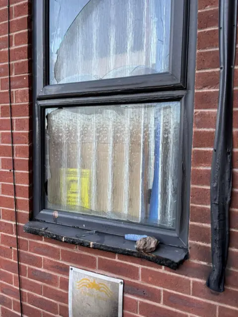 Forever Stars A window with smasehd glass and melted plastic sill next to a pipe which has melted. 