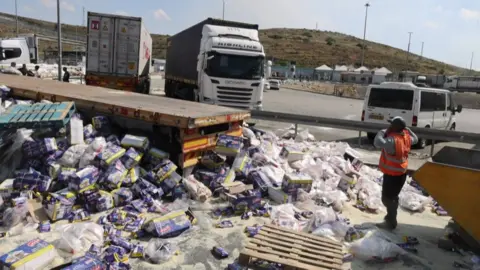 Aid from lorries spilled over the floor at the Tarqumiya checkpoint in the occupied West Bank.