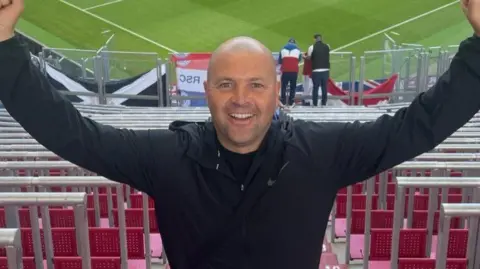 Facebook Christopher Potter with his arms raised at ibrox stadium in front of the seats in the stand