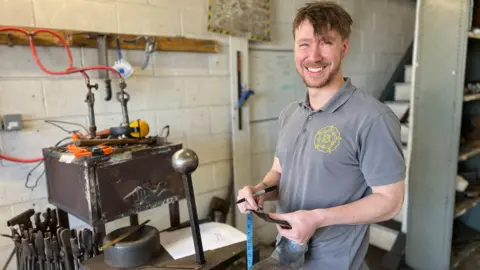 BBC Matt Finchen, stood in his workshop, smiling at the camera