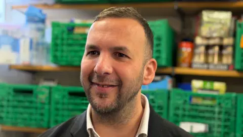 Green Party Leader Zack Polanski, a man in his early forties in a dark suit with dark hair, dark eyes and stubble 