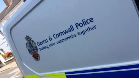 The side of a police van which has the emblem next to the words: Devon & Cornwall Police, Building safer communities together