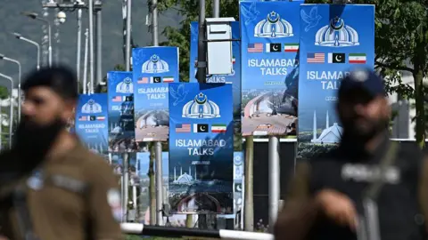 Security personnel stand guard at a security checkpost along a road temporarily closed near the Serena Hotel at the Red Zone area in Islamabad on April 20, 2026.