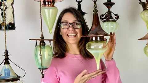 A woman in a pink jumper holding a green light