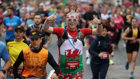 Run 4 Wales Runner wearing sunglasses, toy reindeer ears and a Welsh dragon on his tee-shirt is seen among the competitors