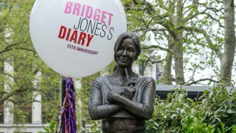 Statue of Bridget Jones holding a pen, beside a balloon which marks the 25th year since the original film was released