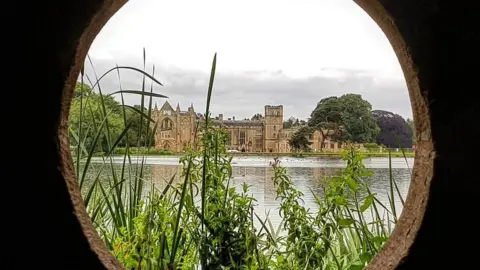 LDRS Newstead Abbey seen across a body of water through a circular hole