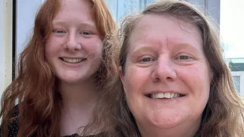 Karen Archenoul Two women smiling, with the one on the left wearing a black top and the one on the right wearing a red printed top