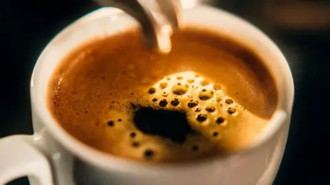 A close-up of a cup of caller espresso retired of an espresso machine.