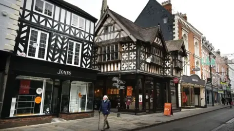 Getty Images An old black and white timber building features on a street in the town among other high streets shops