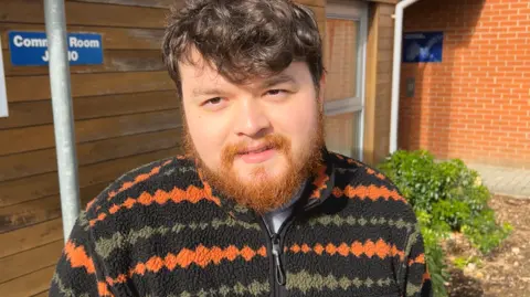 A man with an orange beard. He is wearing a fleece. 