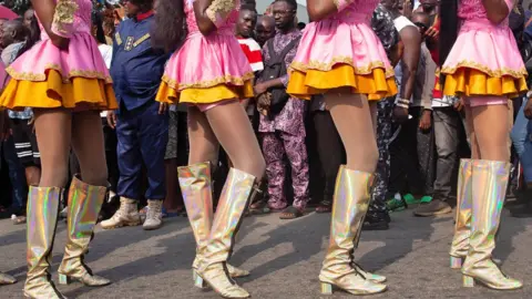 Emmanuel Adegboye / EPA Parade spectators look at the legs of the players wearing gold and pink and orange boots