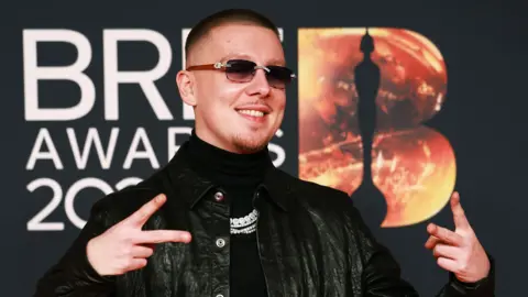 Aitch poses on the red carpet during for the Brit Awards at the Co-op Live Arena in Manchester last month