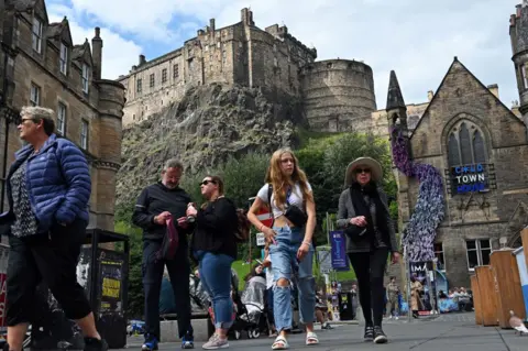 Getty Images People walking along street below Edinburgh Castle
