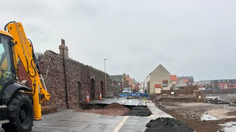 East Lothian Council A tractor is in the foreground. Stones and sand can be seen in the hole.