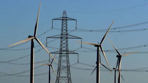 PA Media File photo dated 28/12/17 of a view of the Little Cheyne Court Wind Farm amongst existing electricity pylons on the Romney Marsh in Kent.