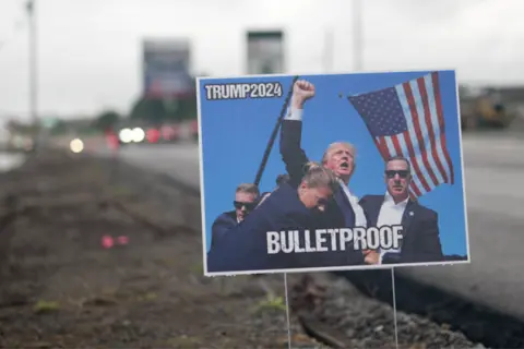 BBC A poster of Trump with blood on his face and his fist raised, with words "Bulletproof"