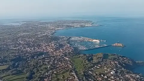 Guernsey from above. Buildings, fields and the sea are all visible. 