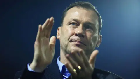 Getty Images Duncan Ferguson applauds. It is night and behind him the spotlight of a football stadium shines.