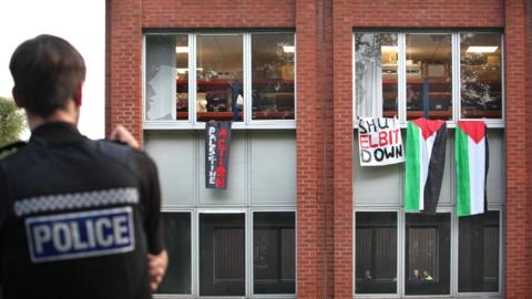A police officer standing in front of a building with protest flags