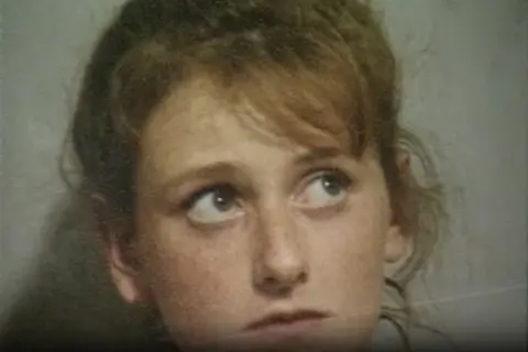Merseyside Police A police mugshot of a young woman with light brown hair glancing up to her left. 